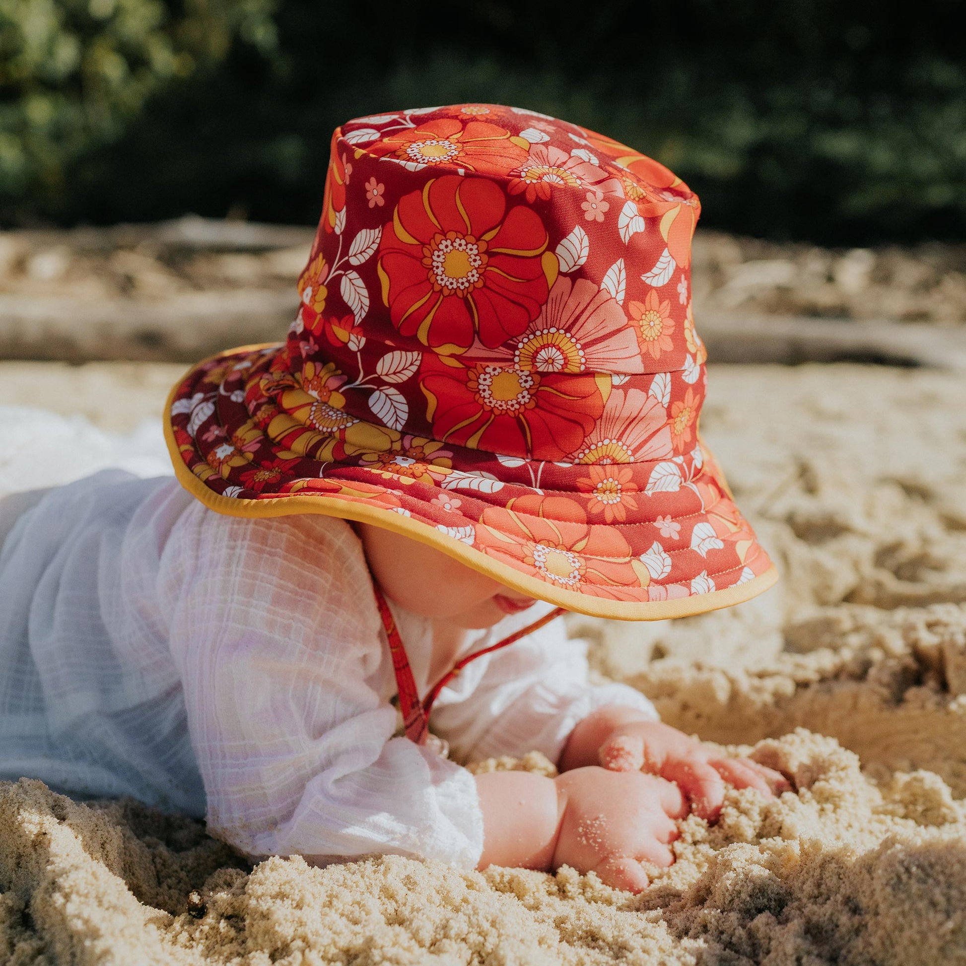 Baby wearing Pipi Swimwear floral and yellow reversible wide brim swim hat