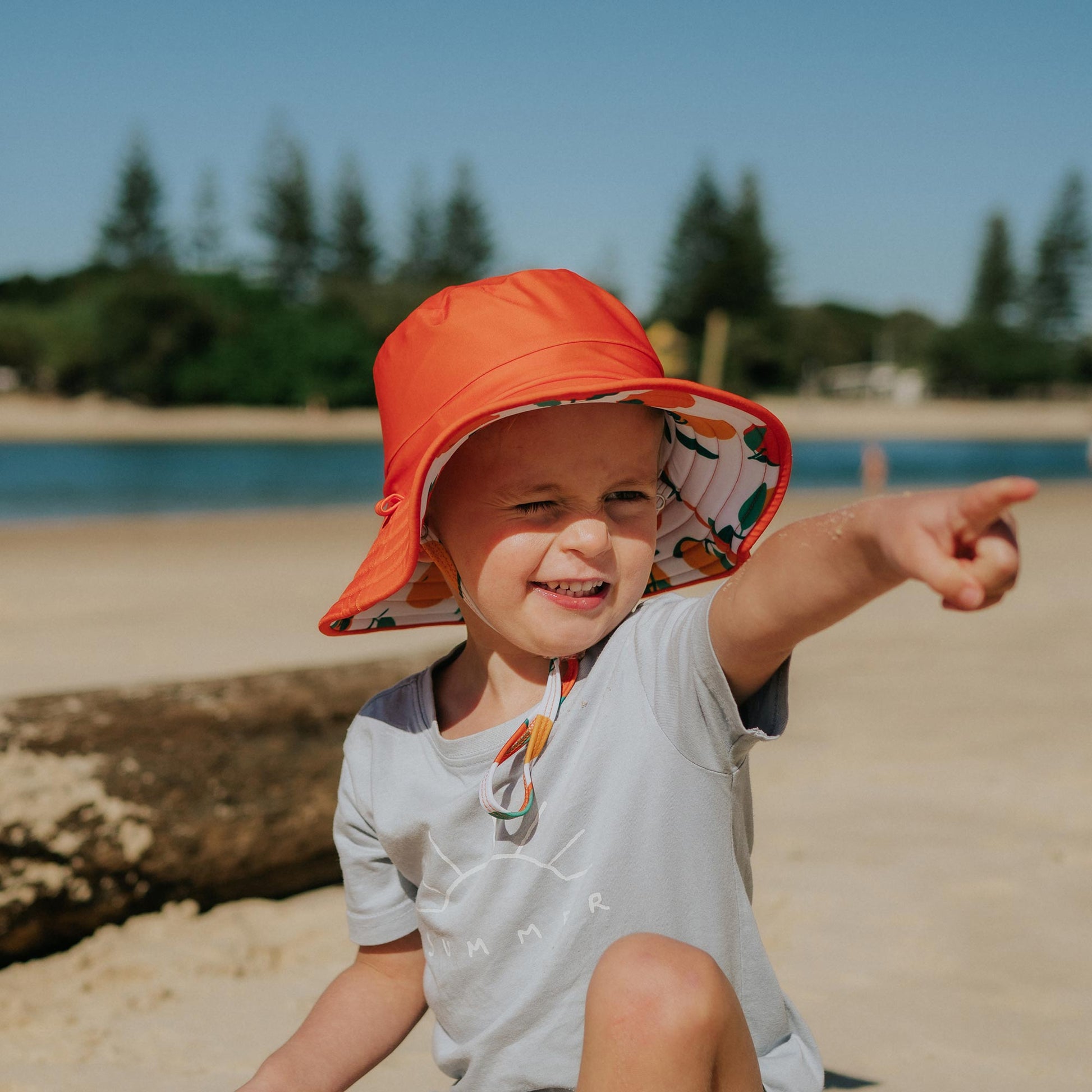 Toddler wearing Pipi Swimwear citrus fruit reversible wide brim swim hat