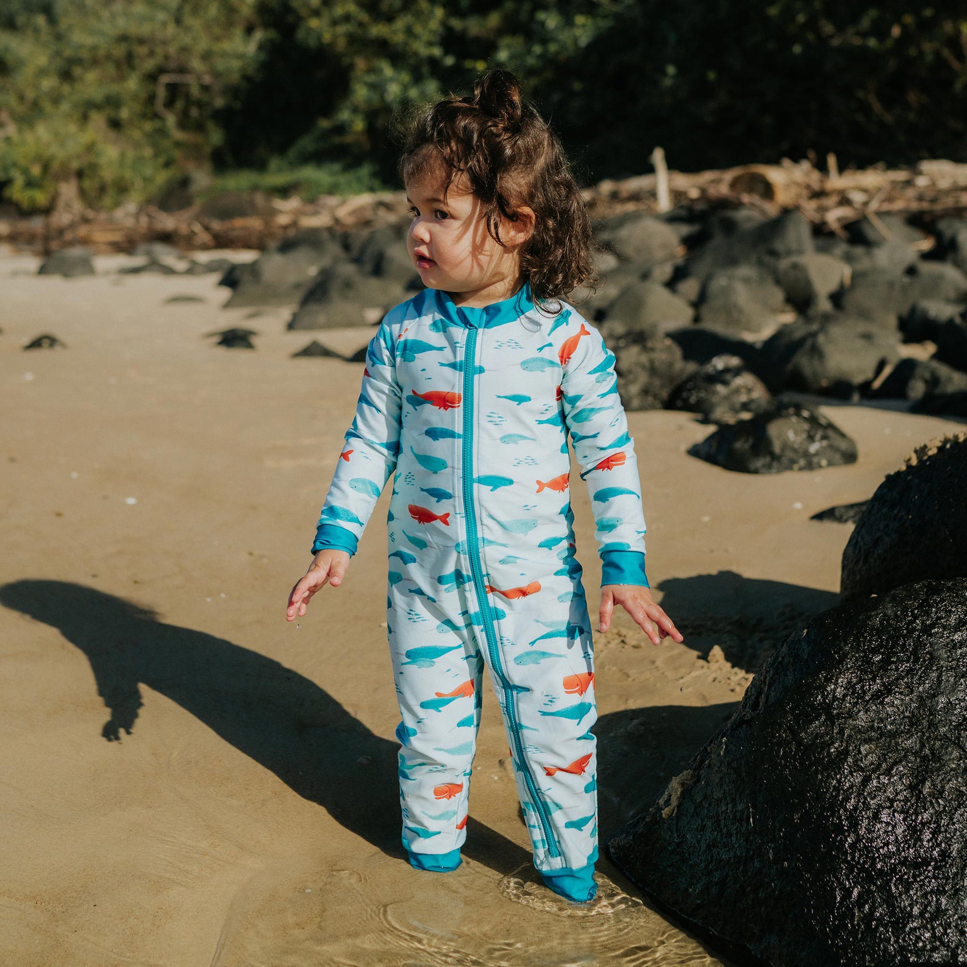 Toddler wearing Pipi Swimwear narwhal full length sunsuit
