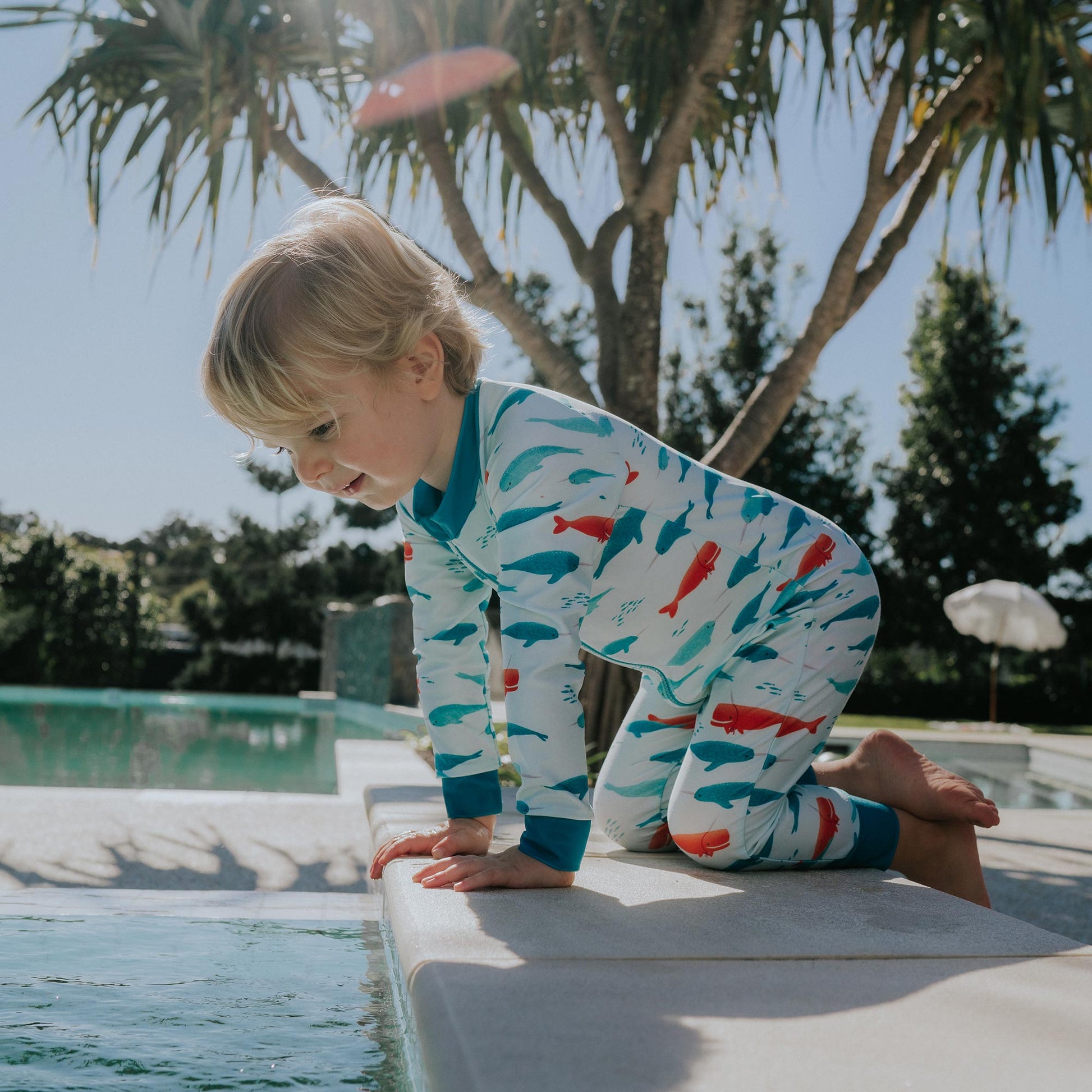 Toddler wearing Pipi Swimwear narwhal full length sunsuit